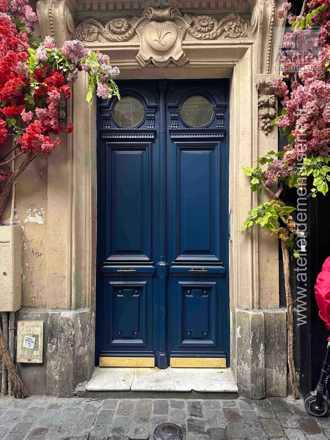 Porte cochère bleu nuit à oculus, encadrement sculpté fleuri, après repose